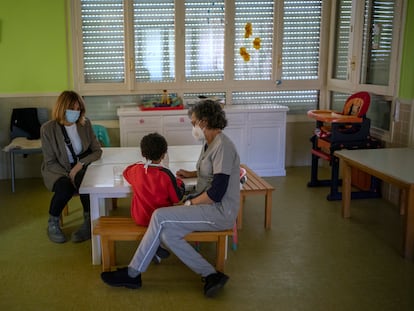 Dos trabajadoras acompañan a un menor mientras come en el centro de menores Juan Pablo II de Segovia.