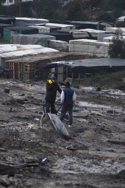 Gran parte de las personas que viven en el asentamiento de Palos de la Frontera afectado por el incendio son temporeros. En la imagen, dos personas conversan, en la parte del poblado que ha quedado reducido a cenizas por el fuego.