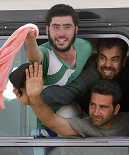 Tres presos recién liberados saludan tras dejar la prisión de Abu Ghraib.