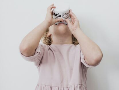 Una niña bebe un vaso de leche.