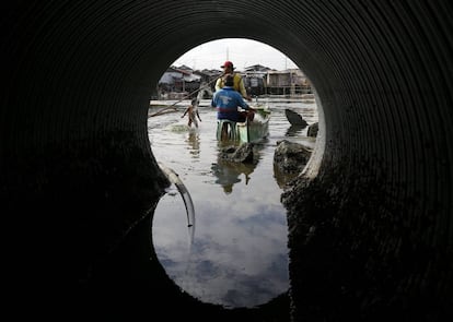 Pescadores filipinos preparan las redes de pesca junto a una cañería de aguas residuales en una zona pesquera de Bacoor (Filipinas).