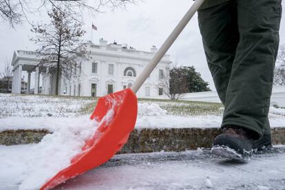 Una persona limpia la nieve, este jueves, en el jardín de la Casa Blanca