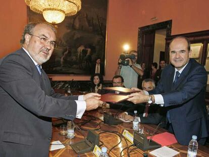 Pedro Solbes (a la izquierda) y Manuel Chaves se intercambian el documento del pago de la deuda para su firma.