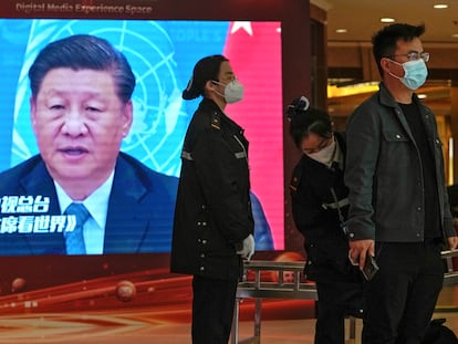 Personal de seguridad cachea a un periodista junto a una pantalla que muestra imágenes del presidente de China, Xi Jinping, en un hotel dedicado a los medios en Pekín, este viernes.