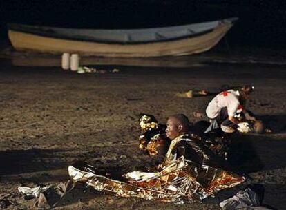 Dos de los inmigrantes del cayuco llegado a Tenerife son atendidos en la playa de Fañabe, en Adeje.