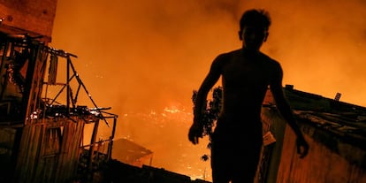 Un residente ayuda durante las labores de los bomberos, en un incendio masivo en el vecindario de Educandos, en Manaus (Brasil).