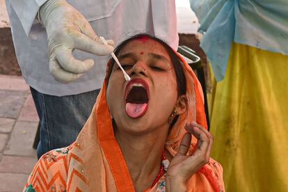 Un sanitario toma una muestra a una mujer para realizar la prueba del coronavirus en un centro de Nueva Delhi, la India.