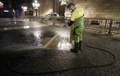 Un treballador del servei de neteja de l'Ajuntament de Barcelona neteja els llaços dibuixats amb pintura sobre el terra de la plaça de Sant Jaume.