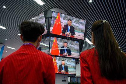 Dos personas siguen un discurso de Xi Jinping en una feria de importación en Shanghái, el día 4.