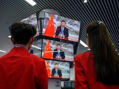 Dos personas siguen un discurso de Xi Jinping en una feria de importación en Shanghái, el día 4.