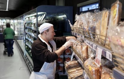 Un empleados repone los productos de panadería en un supermercado