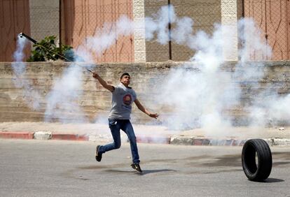 Un manifestante palestino devuelve un bote de gas lacrimógeno a las tropas israelíes durante los enfrentamientos con motivo de las protestas en apoyo a los prisioneros palestinos en huelga de hambre en el asentamiento judío de Beit El, cerca de la ciudad de Ramallah.