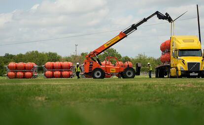 Desde la semana pasada, el Gobierno dirigido por el republicano Greg Abbott comenzó a trasladar boyas naranjas de grandes dimensiones a la frontera entre Eagle Pass y Piedras Negras. En la imagen, un grupo de operarios descarga boyas de un camión, en Eagle Pass, el pasado 7 de julio. 