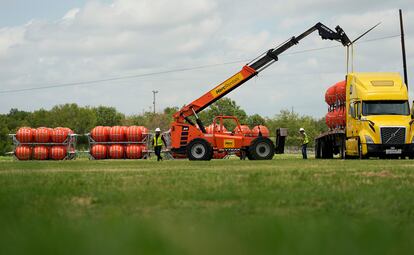 Desde la semana pasada, el Gobierno dirigido por el republicano Greg Abbott comenzó a trasladar boyas naranjas de grandes dimensiones a la frontera entre Eagle Pass y Piedras Negras. En la imagen, un grupo de operarios descarga boyas de un camión, en Eagle Pass, el pasado 7 de julio.