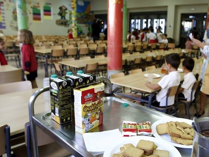 Dos trabajadoras y varios alumnos en un comedor escolar.