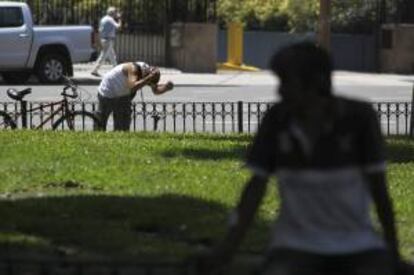 Unos argentinos se refrescan en aspersores de agua en el centro de Buenos Aires (Argentina).