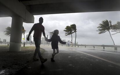 Dos personas caminan por una calle de Miami cuando el huracán se acerca a Florida.
