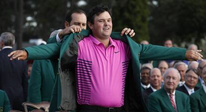 Sergio García ayuda a Patrick Reed a colocarse la chaqueta verde.