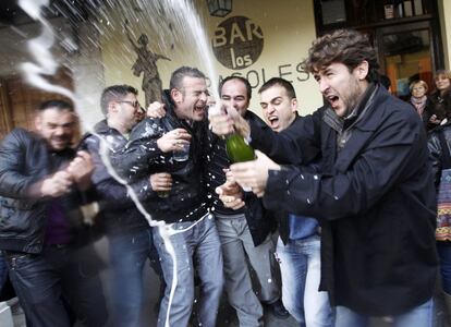 Un grupo de personas festejan el segundo premio del Sorteo Extraordinario de Lotería de Navidad de 2014 a la salida de un bar de Aranda de Duero (Burgos), donde se vendió íntegramente el número 42.260.