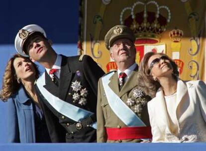 Los príncipes de Asturias y los Reyes observan cómo uno de los paracaidistas de la patrulla acrobática del Ejército del Aire cae sobre la plaza de Colón portando la bandera española.