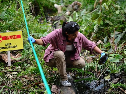 Una mujer muestra una botella cubierta con petróleo, en una imagen de 2013 en la región amazónica de Ecuador.