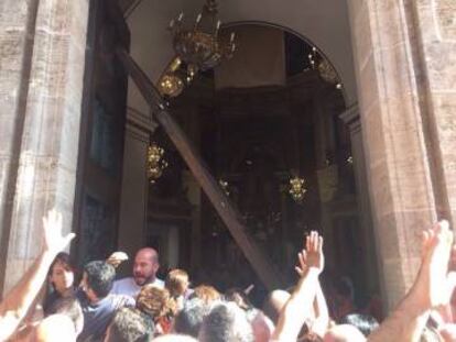 Fieles en la basílica de Valencia, una de cuyas puertas se ha desprendido.