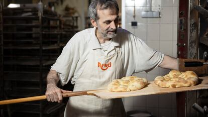 El panadero Daniel Jordà retira dos piezas recién horneadas en su obrador de Barcelona, 'Panes Creativos'.