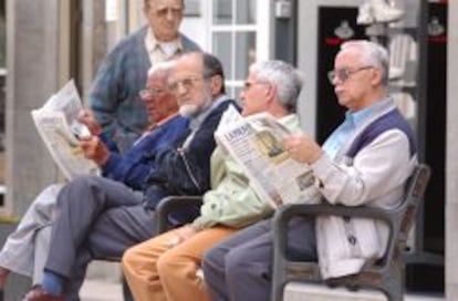 Varios pensionistas jubilados leen el periódico.