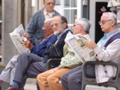 Varios pensionistas jubilados leen el periódico.