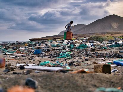 Un hombre recoge plástico y basura de una playa.