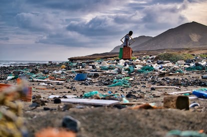 Un hombre recoge plástico y basura de una playa.