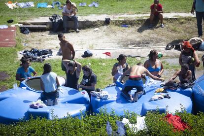 Un grupo de migrantes se ducha en bidones de agua en 'ciudad Palillo', como se apodó al albergue en Ciudad de México.