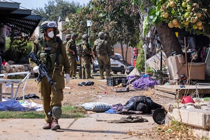 Soldados israelíes, este martes cerca del cuerpo de un militante palestino en Kfar Aza, en el sur de Israel, en la frontera con la franja de Gaza.