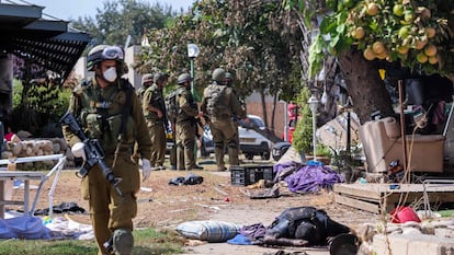 Soldados israelíes, este martes cerca del cuerpo de un militante palestino en Kfar Aza, en el sur de Israel, en la frontera con la franja de Gaza.