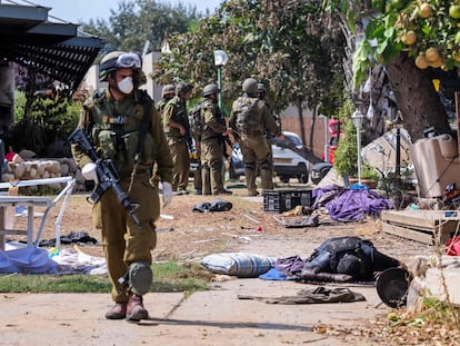 Soldados israelíes, este martes cerca del cuerpo de un militante palestino en Kfar Aza, en el sur de Israel, en la frontera con la franja de Gaza.