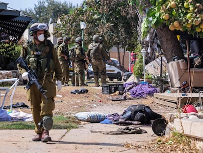 Un soldado israelí pasa junto al cadáver de un miembro de Hamás en la localidad israelí de Kfar Aza.