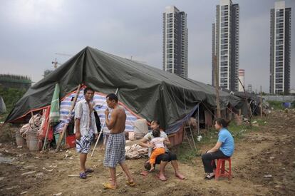 Trabajadores inmigrantes descansan frente a su tienda cerca de un &aacute;rea de construcci&oacute;n residencial.