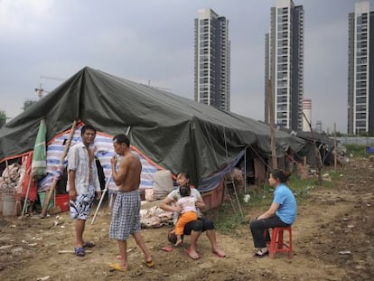 Trabajadores inmigrantes descansan frente a su tienda cerca de un &aacute;rea de construcci&oacute;n residencial.