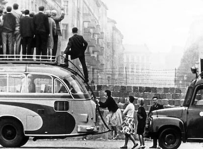 Un grupo de turistas subidos al techo de un autobús para observar el lado oriental de Berlín.