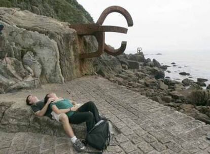 Una pareja junto a &#39;El Peine de los Vientos&#39;, espacio diseñado por Peña Ganchegui con esculturas de Eduardo Chillida, en San Sebastián.