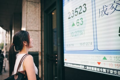 Asian businesswoman looking at stock quote board