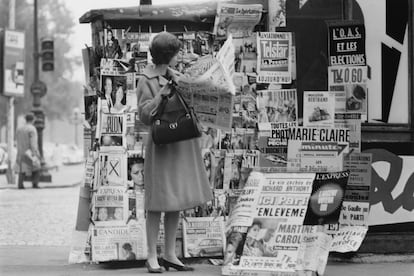 Liz Karlson, editora de ropa deportiva de la revista Glamour, leyendo el periódico en un quiosco de París. 
