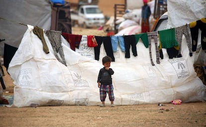 A displaced Syrian child, who fled the countryside surrounding the Islamic State (IS) group stronghold of Raqa, stands while looking on at a temporary camp in the village of Ain Issa on April 28, 2017. / AFP PHOTO / DELIL SOULEIMAN