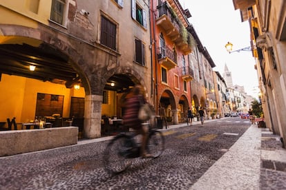En la imagen, una ciclista atraviesa las calles de Verona.