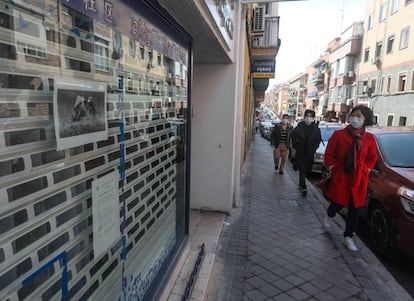 Un comercio cerrado en el distrito madrileño de Usera, este martes, ante el que varios viandantes pasan con mascarillas como protección ante el contagio de la Covid-19.