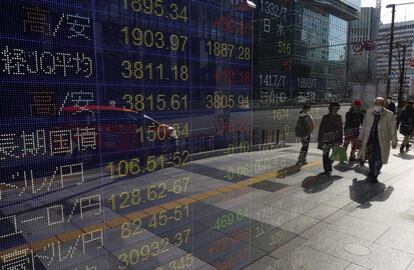 Varias personas pasan junto a una cristalera donde se reflejan los valores de la Bolsa de Tokio. El principal índice de la Bolsa de Tokio, el Nikkei, subió un 2,41 % este lunes después de que los inversores se lanzaran a la caza de gangas tras la pronunciada caída experimentada por el selectivo en la sesión previa el pasado viernes.