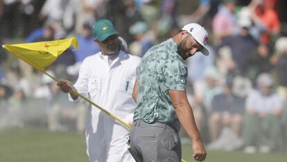 Jon Rahm y su caddie, protegiéndose del viento.