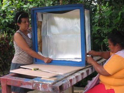 Unas mujeres construyen una cocina solar. 