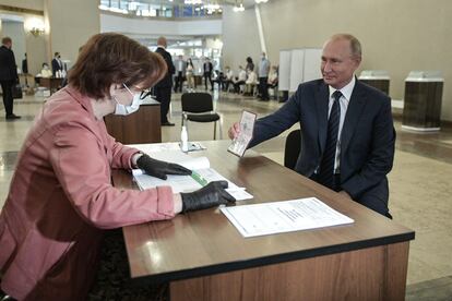 Putin muestra su identificación antes de emitir su voto en un referéndum.