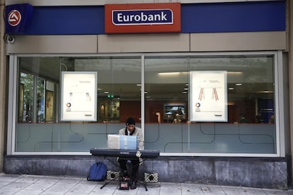 A street musician plays his instrument outside a Eurobank branch in central Athens October 27, 2014. Greek bank deposits rose in September for the seventh straight month, central bank data showed on Monday. Business and household deposits rose to 164.75 billion euros ($209.2 billion) from 164.23 billion euros in August, the Bank of Greece said. REUTERS/Yorgos Karahalis (GREECE - Tags: BUSINESS POLITICS SOCIETY)